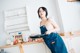 A woman in an apron holding a frying pan in a kitchen.
