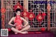 A woman in a red dress sitting on a table.