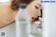 A woman drinking water from a glass in a bathroom.