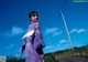 A woman in a purple kimono standing on the side of a road.