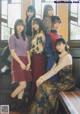 A group of young women sitting on top of a wooden bench.