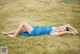 A woman in a blue dress laying on the grass.