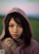 A young woman in a pink hooded jacket is posing for a picture.