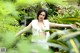 A woman standing in the middle of a lush green forest.