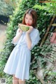 A woman in a blue and white striped dress holding a watermelon.