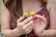 A woman holding two yellow dandelions in her hands.