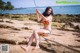 A woman in a bikini sitting on a swing on the beach.